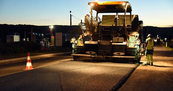 Application d&rsquo;enrob&eacute; de nuit avec finisseur et &eacute;quipe de travaux routiers