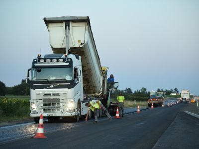 Camion benne en cours de déchargement d’enrobé lors de travaux routiers