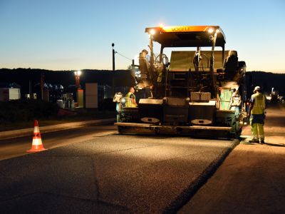 Finition de chaussée de nuit avec finisseur et équipe de travaux publics