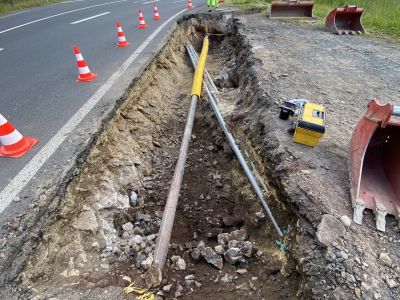 Pose de canalisations dans une tranchée en bord de route lors de travaux publics